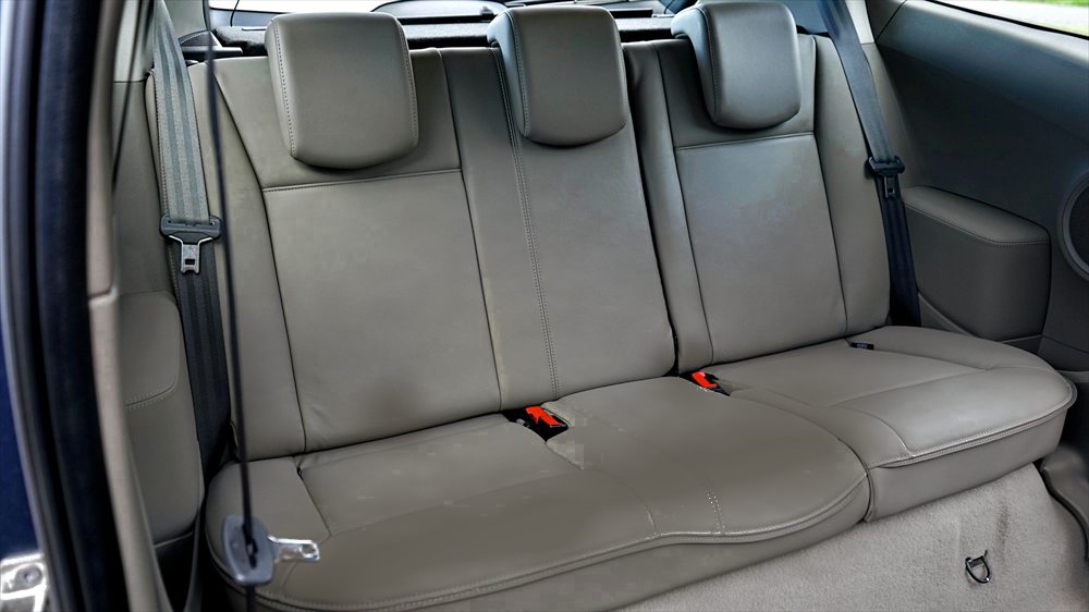 The same car rear seats before cleaning, dulled and marked across the seat backs