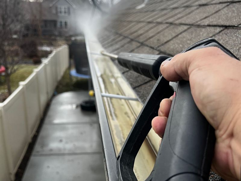 Water being sprayed along a gutter on an asphalt shingle roof